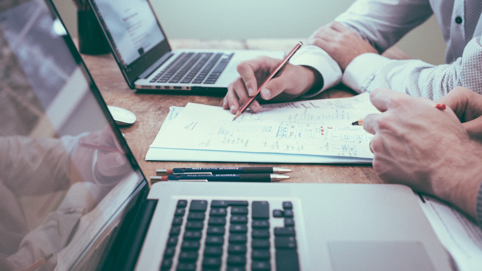 Investors reviewing deal documents and property numbers at a table